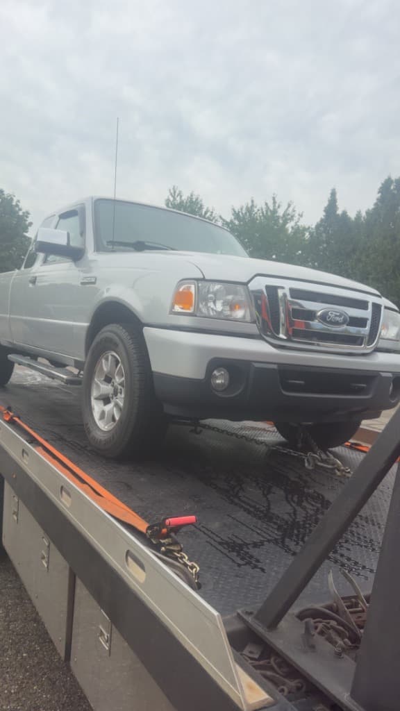 White Ford Ranger pickup truck strapped down on a Ritchie Express Towing flatbed
