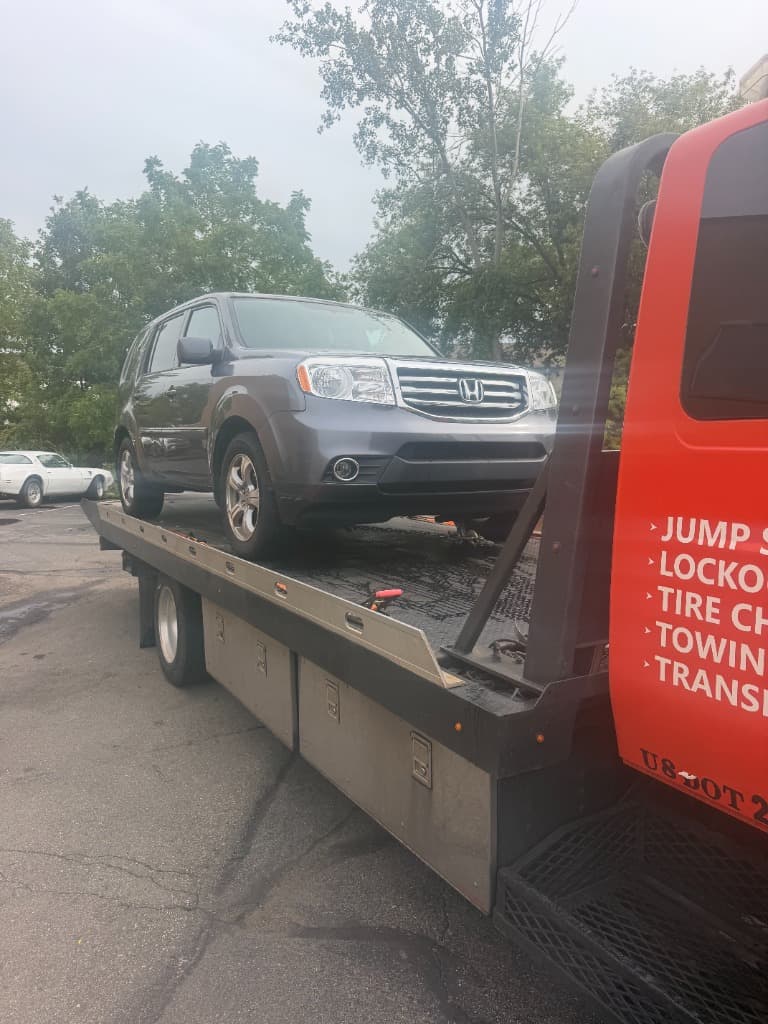 Gray Honda Pilot loaded onto a Ritchie Express Towing flatbed truck